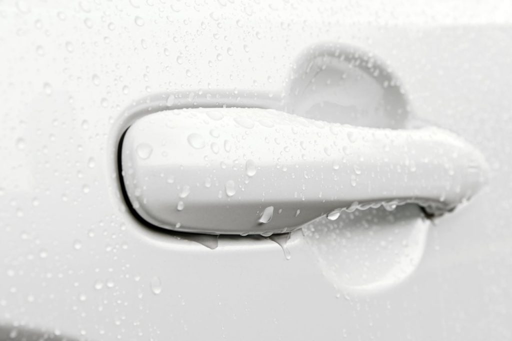 pexels-photo-17216295 Detailed image of a car door handle covered in raindrops, capturing a wet and rainy environment.